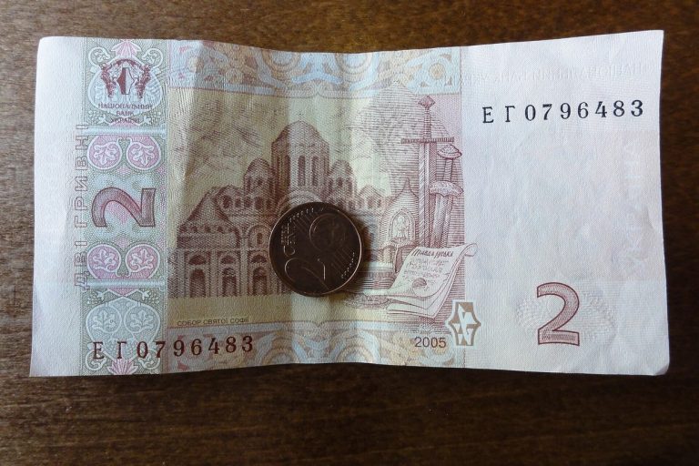 Банкнота 2 гривні і монета на дерев'яному столі
